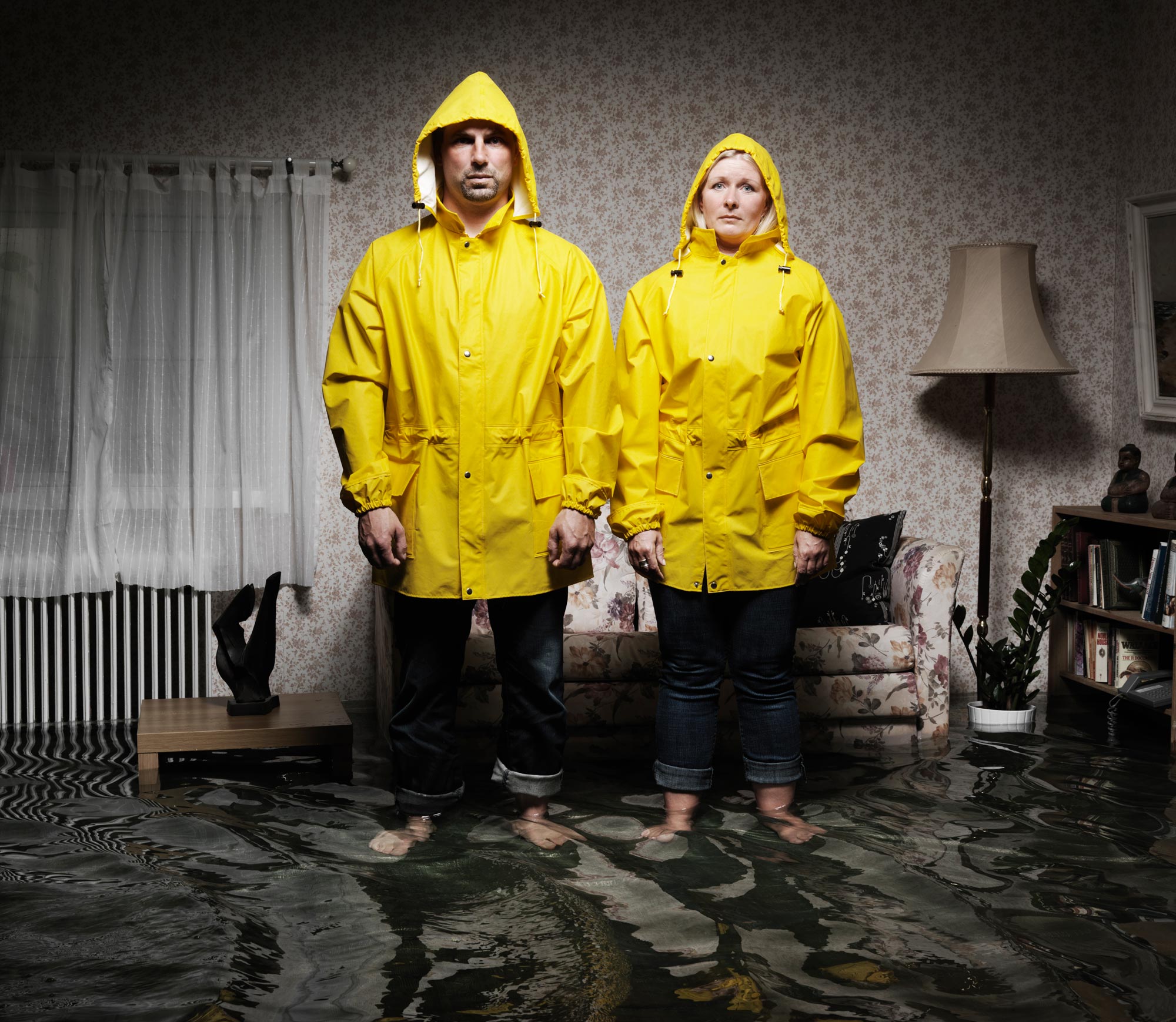 Kvinna och man som står i regnkläder i en villa