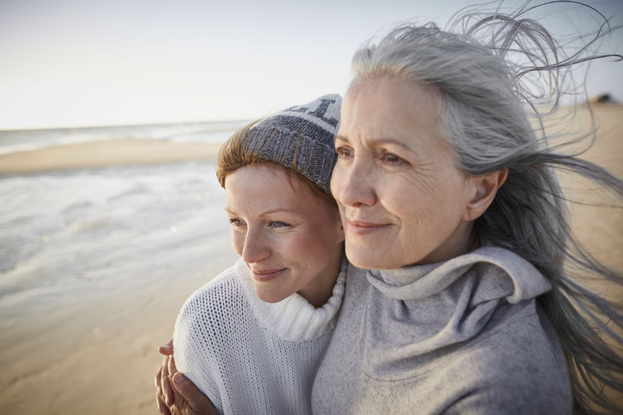 Mor och dotter håller om varandra på en strand.