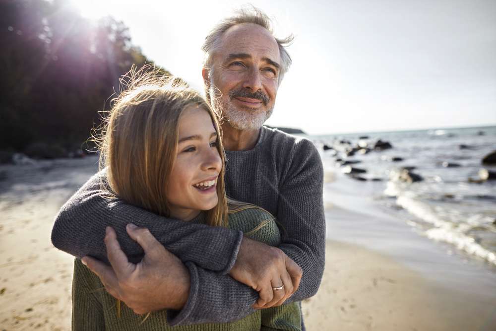 Pappa kramar sin dotter på stranden.